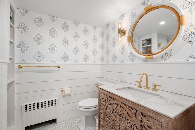 bathroom with radiator, wood walls, vanity, toilet, and tile patterned floors