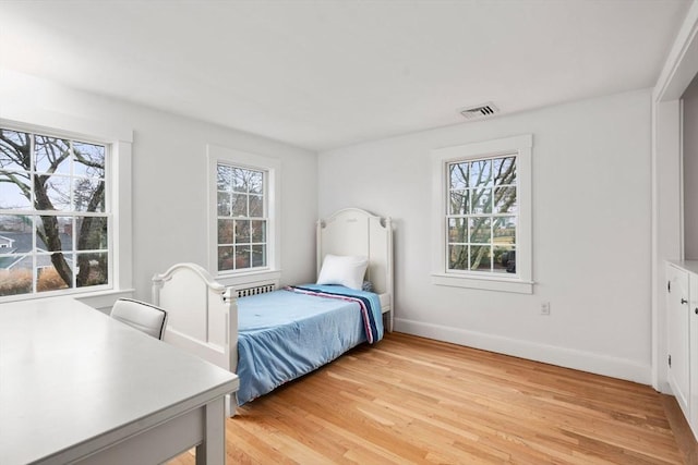 bedroom with multiple windows and light hardwood / wood-style floors