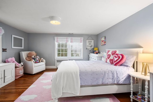 bedroom with dark wood-type flooring and radiator heating unit