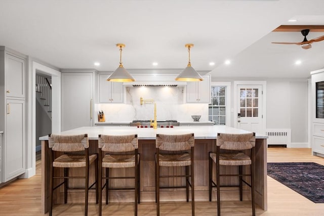 kitchen with a spacious island, a breakfast bar, radiator, and hanging light fixtures