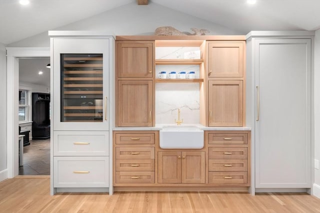 bar with wine cooler, lofted ceiling, light hardwood / wood-style floors, and sink