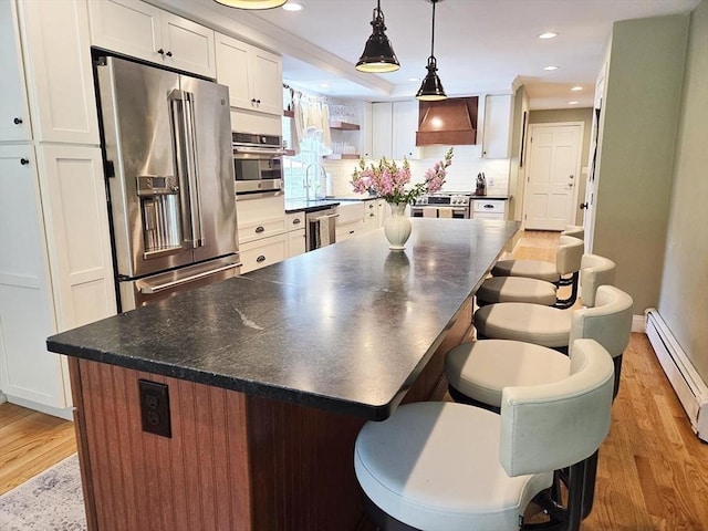 15 Sudbury Rd, Stow, MA 01775 - kitchen featuring stainless steel appliances, baseboard heating, premium range hood, dark countertops, and light wood finished floors