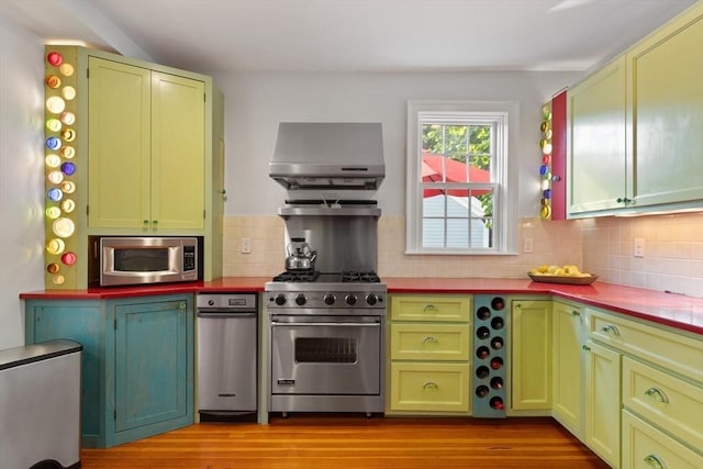 1395 Canton Ave, Milton, MA 02186 - kitchen featuring stainless steel appliances, wall chimney exhaust hood, decorative backsplash, light wood-style flooring, and green cabinets