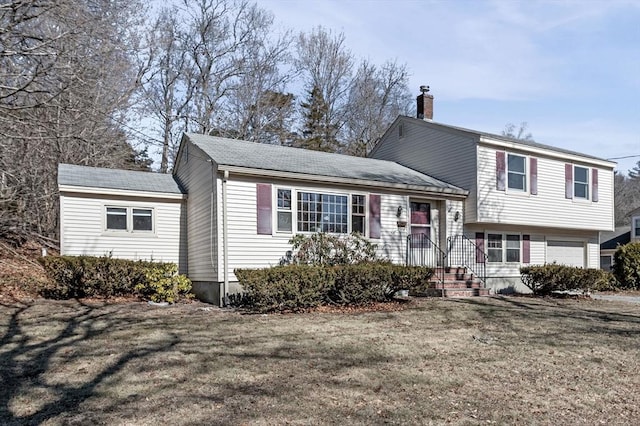 split level home with a garage, a chimney, and a front yard