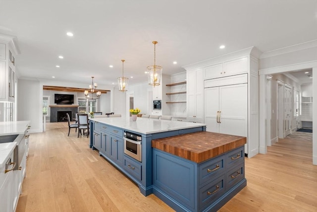 kitchen featuring recessed lighting, white cabinets, wooden counters, and blue cabinetry