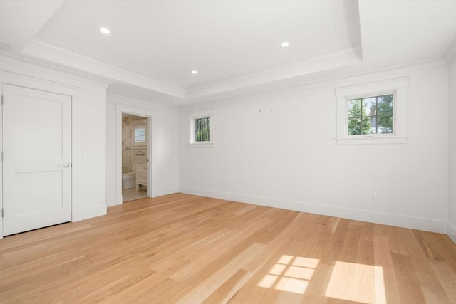 unfurnished bedroom featuring light wood-style floors, a raised ceiling, ornamental molding, and baseboards