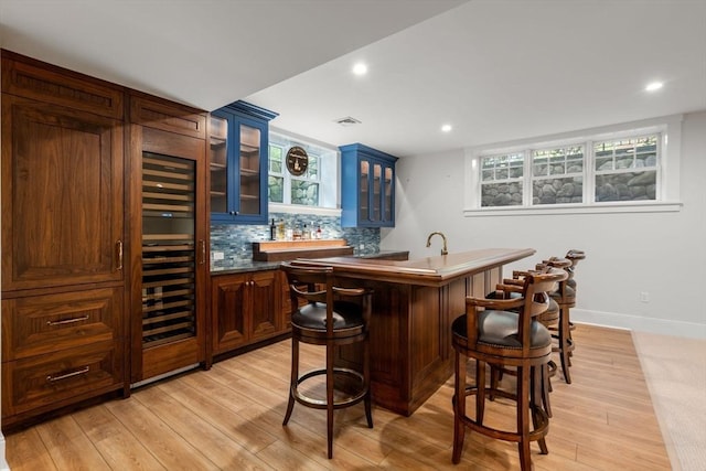 bar with wet bar, light wood-type flooring, wine cooler, backsplash, and visible vents