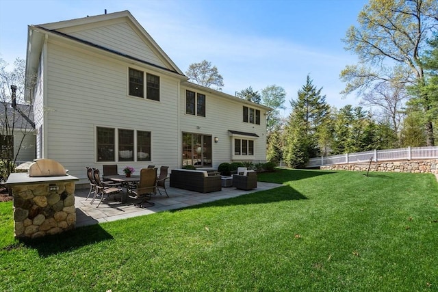 rear view of property with a lawn, exterior kitchen, fence, and a patio area