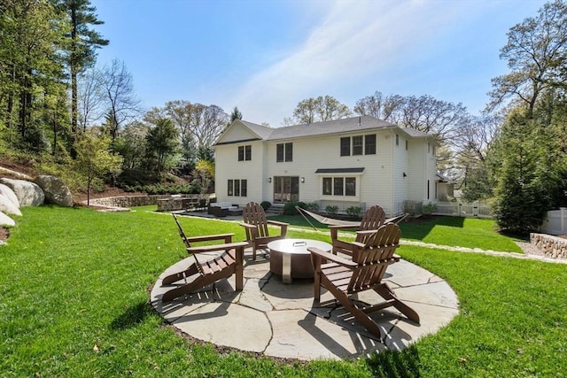 rear view of house with a lawn, a fire pit, and a patio area