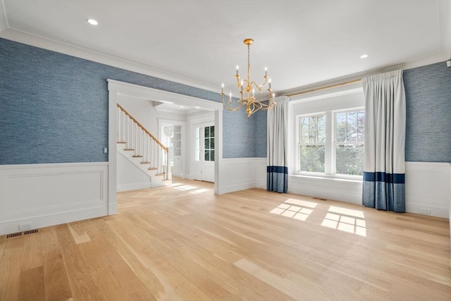 unfurnished dining area featuring a wainscoted wall, a wealth of natural light, wood finished floors, and a chandelier
