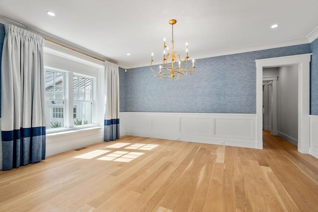empty room with visible vents, wainscoting, wood finished floors, and a chandelier