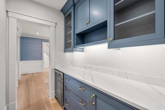 kitchen with blue cabinetry, glass insert cabinets, a wainscoted wall, and wine cooler
