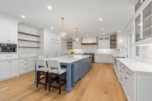 kitchen with white cabinets, open shelves, premium range hood, and blue cabinets