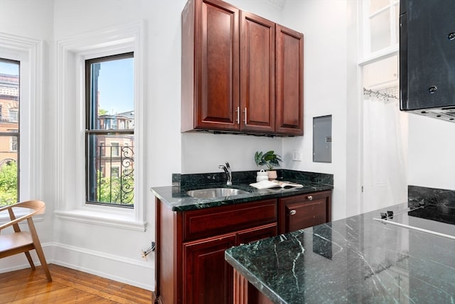 kitchen with sink, plenty of natural light, light hardwood / wood-style floors, and dark stone counters