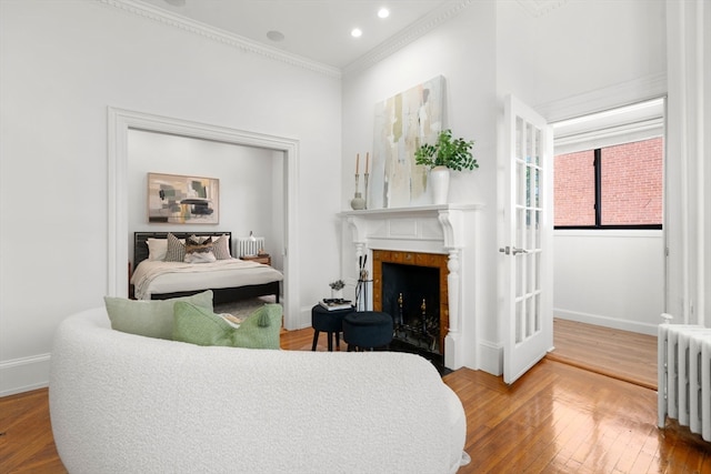 bedroom featuring wood-type flooring, radiator, and crown molding