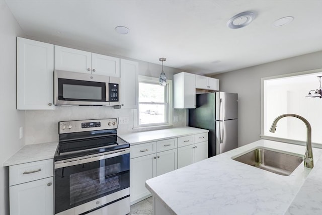 24 Harwich Rd, East Longmeadow, MA 01028 - kitchen featuring appliances with stainless steel finishes, a sink, white cabinetry, decorative light fixtures, and light stone counters