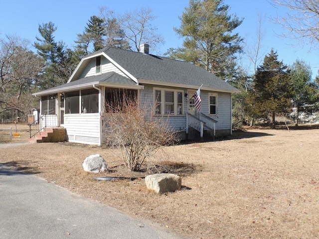 view of front of house with roof with shingles, a sunroom, and a chimney