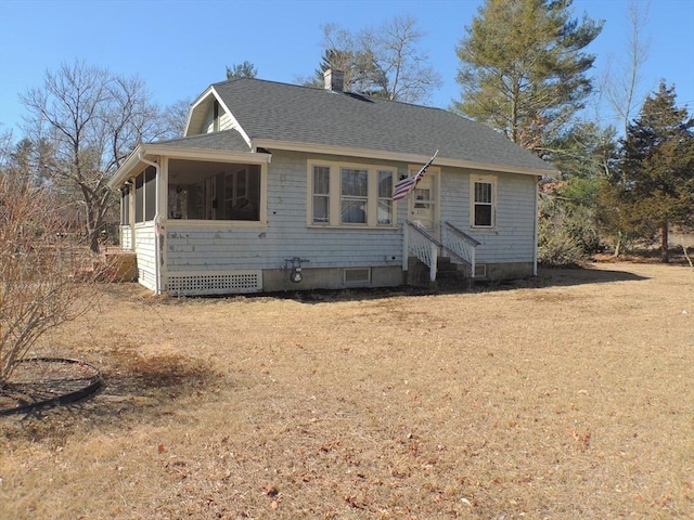 view of front of house featuring a sunroom, a front yard, and a shingled roof