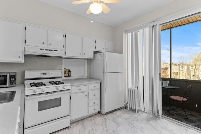 kitchen featuring under cabinet range hood, white appliances, radiator heating unit, and light countertops