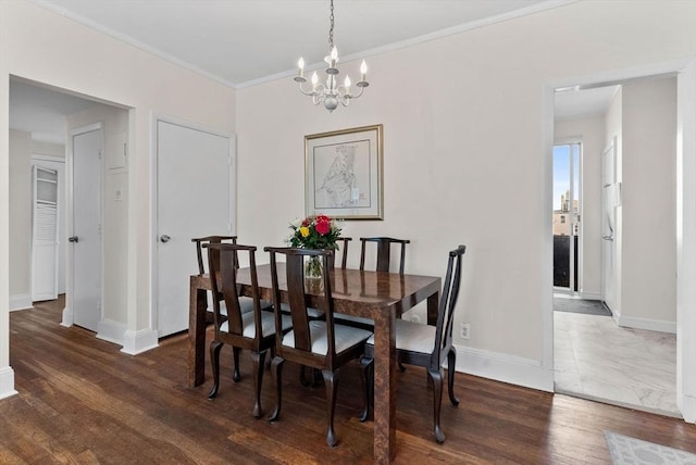 dining room featuring a chandelier, baseboards, wood finished floors, and crown molding