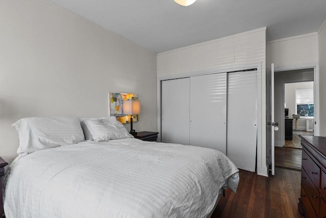 bedroom featuring dark wood-type flooring, a closet, and crown molding