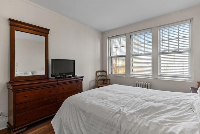 bedroom with radiator heating unit, dark wood-style floors, and ornamental molding