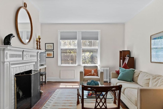 living area with radiator heating unit, a fireplace, and baseboards