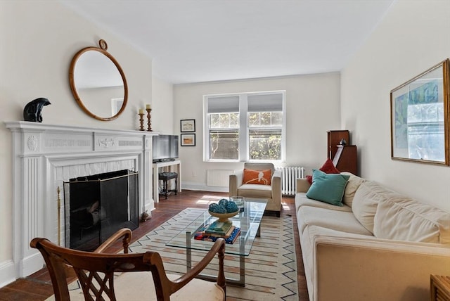 living room with radiator, a fireplace with flush hearth, dark wood-type flooring, and baseboards