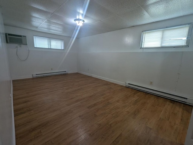 300 Smithfield Rd Unit 2-2, North Providence, RI 02904 - below grade area with baseboard heating, wood finished floors, a wall unit AC, and a drop ceiling
