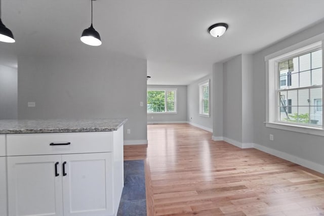 21 Stephanie St Unit 1, Gardner, MA 01440 - kitchen with light wood-type flooring, white cabinets, open floor plan, light stone countertops, and hanging light fixtures
