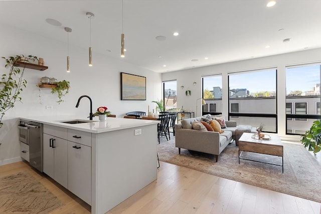 340 W 2nd St Unit 23, Boston, MA 02127 - kitchen with a sink, dishwasher, light wood-style floors, open shelves, and a peninsula