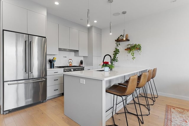 340 W 2nd St Unit 23, Boston, MA 02127 - kitchen with high quality fridge, a sink, a breakfast bar area, light wood-style flooring, and light countertops