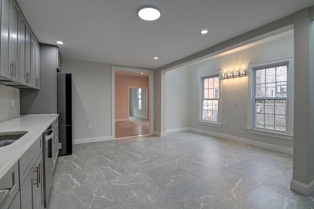 kitchen featuring light stone counters, gray cabinets, and marble finish floor
