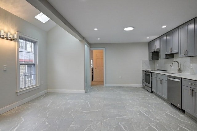 kitchen with a sink, appliances with stainless steel finishes, gray cabinets, and marble finish floor