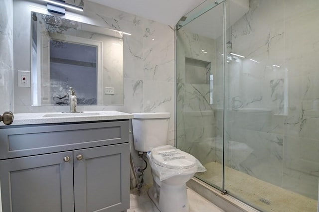 bathroom with toilet, tile walls, a marble finish shower, and vanity