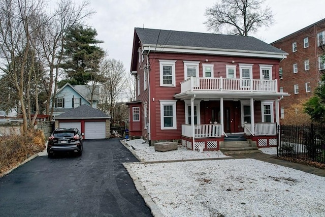 view of front of house with fence, a detached garage, a porch, an outbuilding, and a balcony