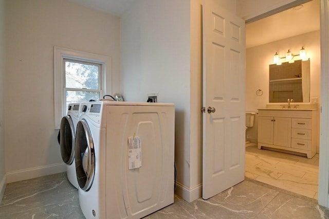 clothes washing area with a sink, baseboards, washer and dryer, and marble finish floor