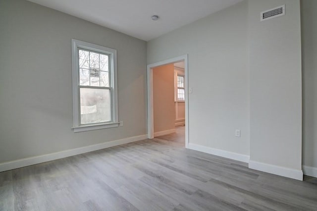 empty room featuring baseboards, visible vents, and wood finished floors