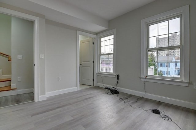 unfurnished room with baseboards, wood finished floors, and stairway