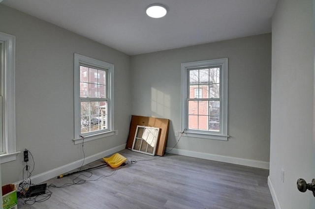 spare room featuring baseboards and wood finished floors