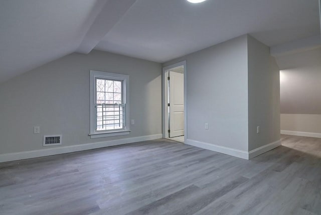 bonus room featuring baseboards, visible vents, wood finished floors, and lofted ceiling