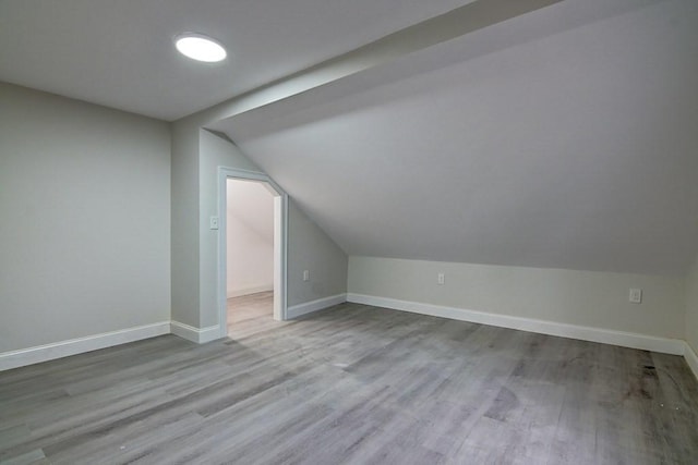 additional living space with wood finished floors, baseboards, and lofted ceiling