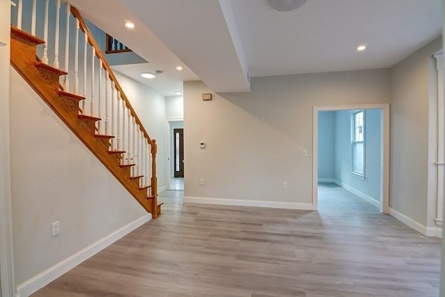 unfurnished living room with stairs, recessed lighting, baseboards, and light wood-style flooring