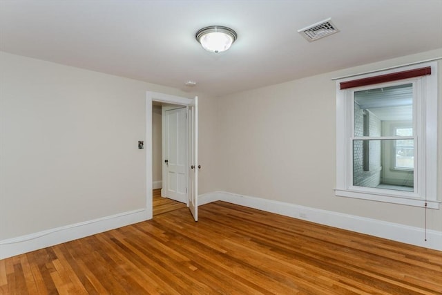 unfurnished room with visible vents, baseboards, and wood finished floors