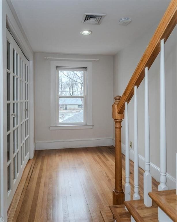 doorway with baseboards, stairway, visible vents, and light wood-style floors