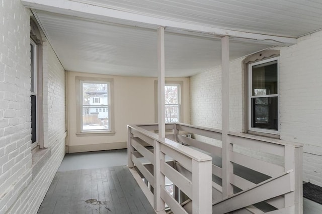 interior space with brick wall and hardwood / wood-style floors