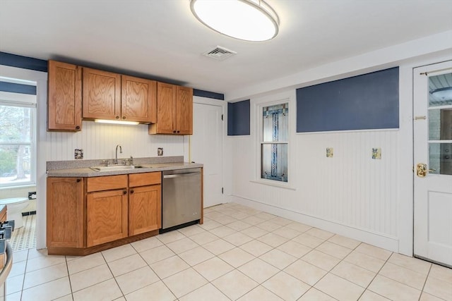 kitchen with stainless steel dishwasher, brown cabinetry, a sink, and visible vents