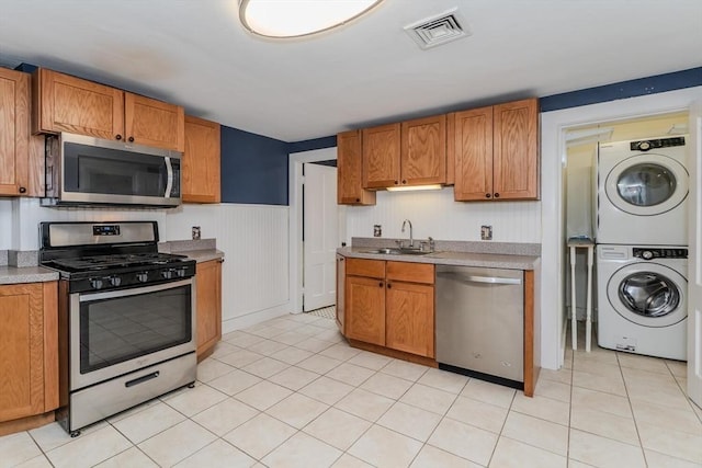 kitchen with stacked washer and dryer, a sink, visible vents, light countertops, and appliances with stainless steel finishes