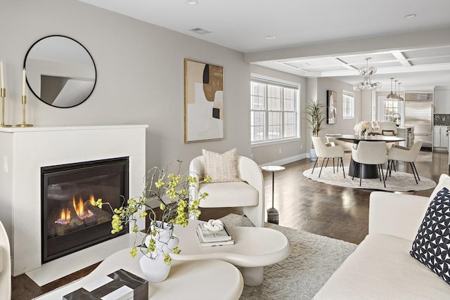 living room with a notable chandelier, coffered ceiling, hardwood / wood-style floors, and beamed ceiling