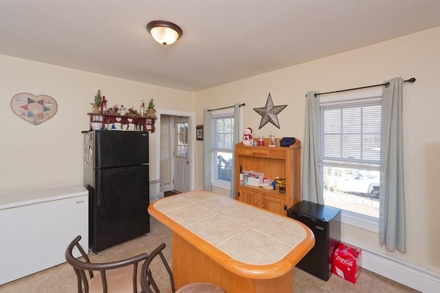 kitchen featuring kitchen peninsula, tile countertops, fridge, black refrigerator, and light tile patterned flooring